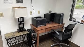 A home office setup with a desk, computer, printer, and a chair.
