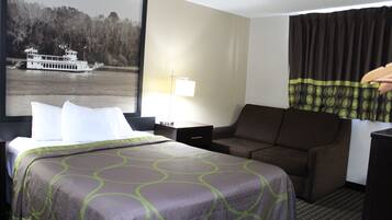 A hotel room with a bed, a sofa, a desk, and a large window with a view of a river and trees.
