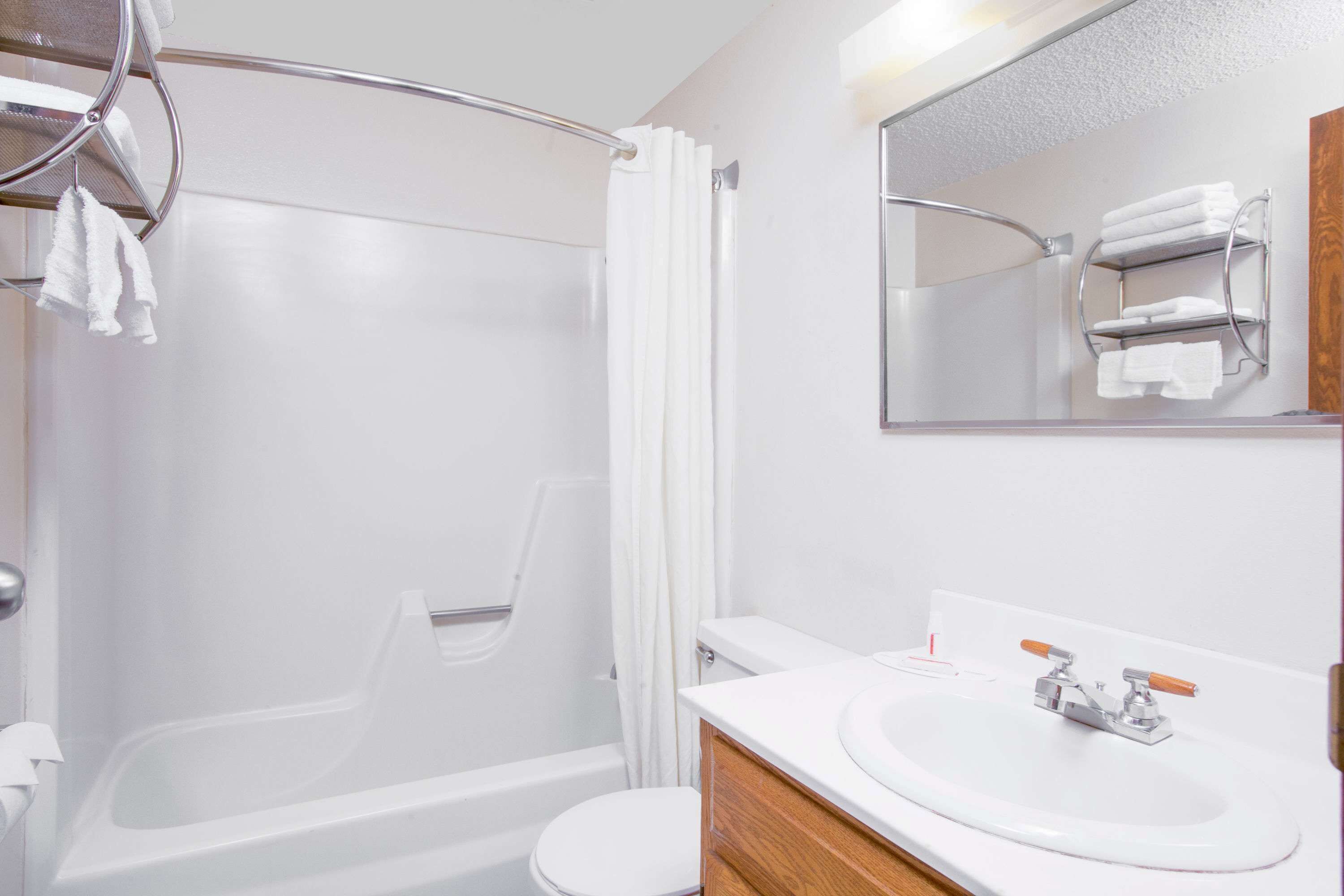 A bathroom with a bathtub, toilet, and a sink with a mirror above it.