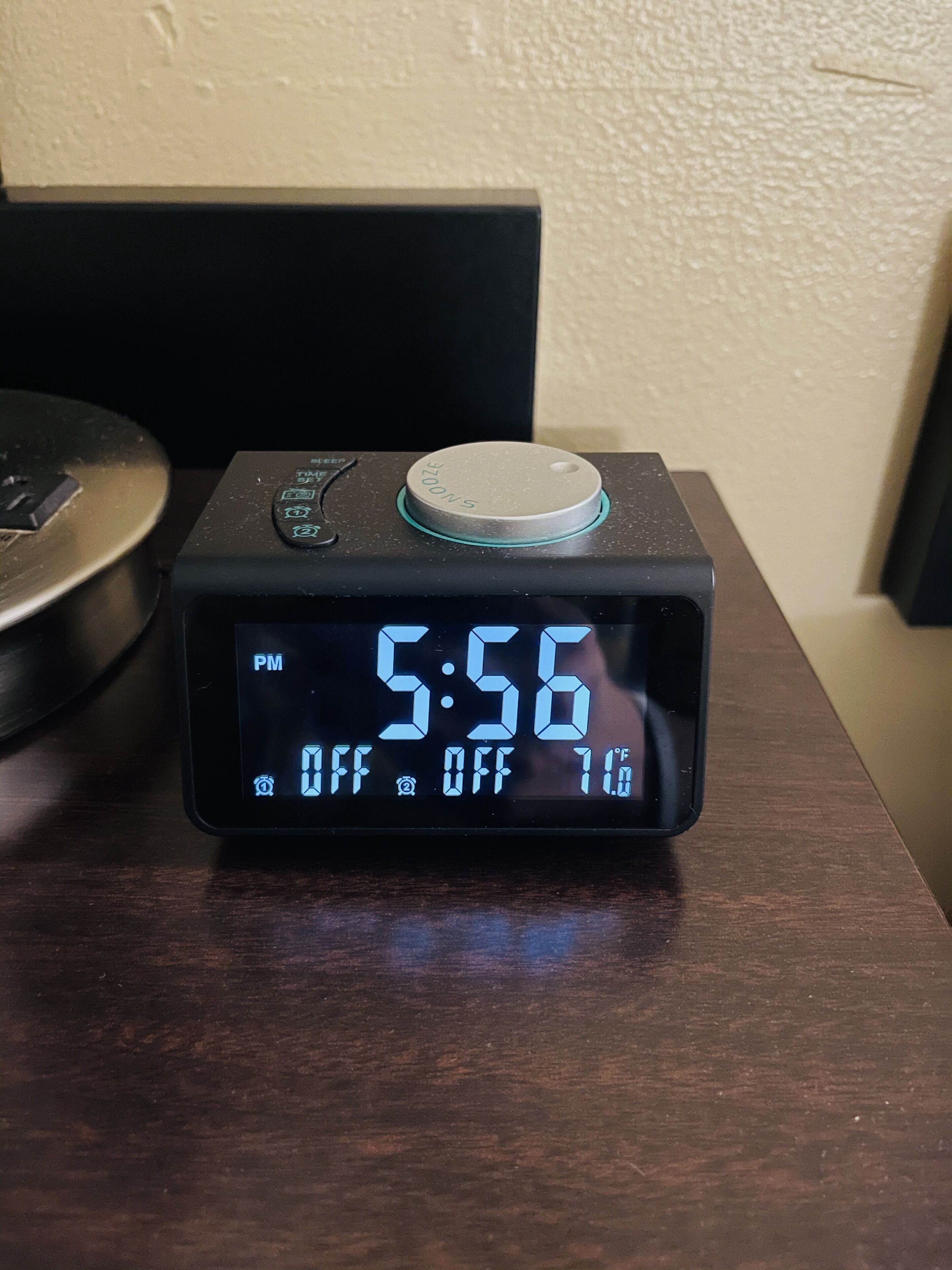 Eine digitale Uhr zeigt 17:56 Uhr an, die Temperatur beträgt -12 Grad Fahrenheit und es befindet sich ein Power-Knopf auf einer Holzoberfläche.