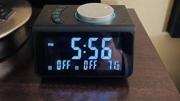 Eine digitale Uhr zeigt 17:56 Uhr an, die Temperatur beträgt -12 Grad Fahrenheit und es befindet sich ein Power-Knopf auf einer Holzoberfläche.