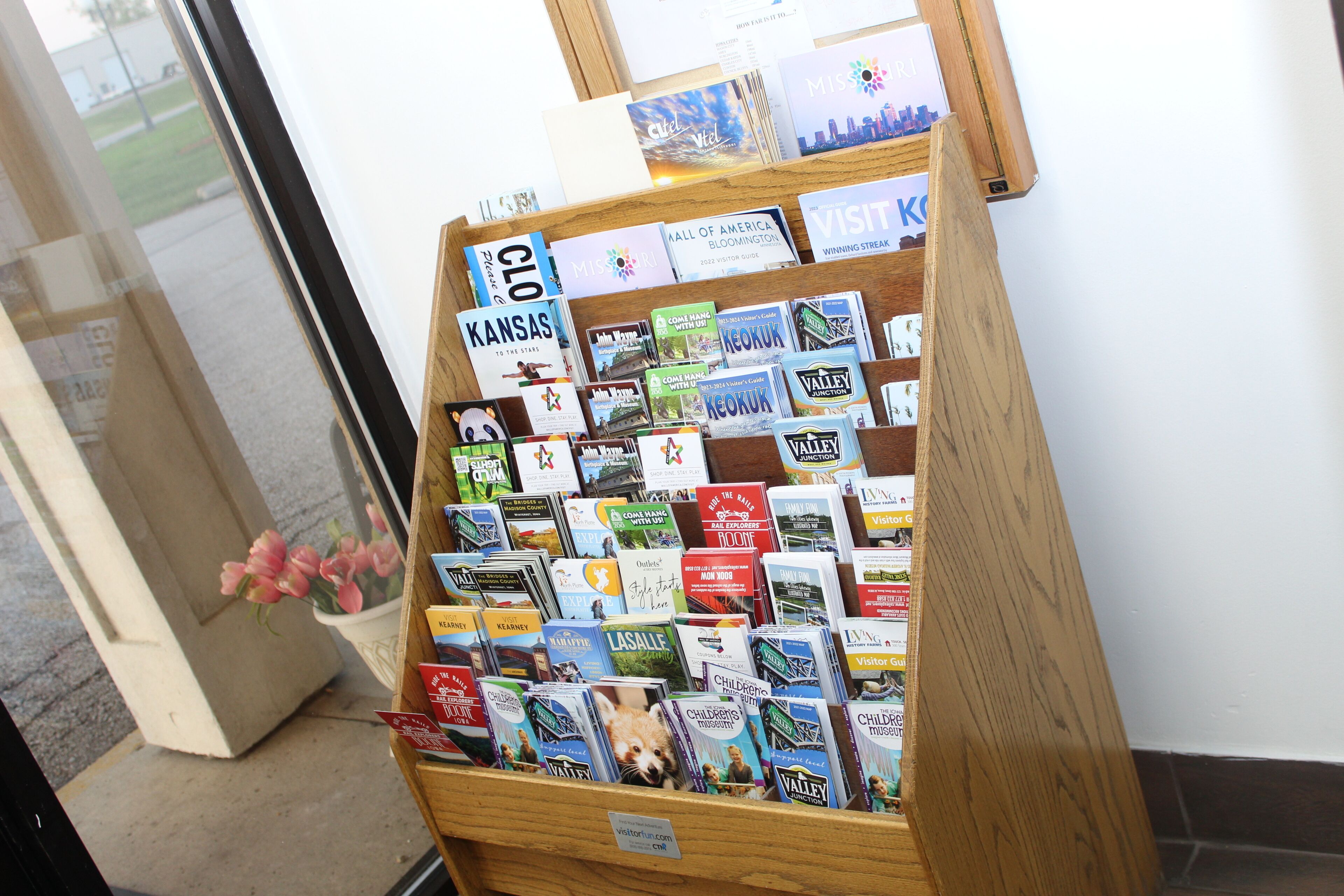 A display of travel guides and maps in a wooden stand.