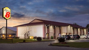 A Super 8 motel with a large garage door, a staircase leading to the entrance, and several parked cars in the driveway.