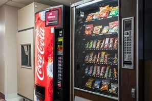 En automattank med Coca-Colas logotyp och en annan automat bredvid som säljer snacks.