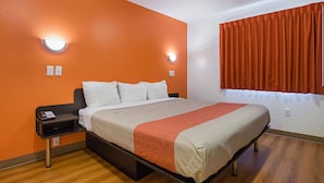 A hotel room with a bed, a nightstand, and a window with curtains. - Motel 6 Marshalltown, IA (Marshalltown)