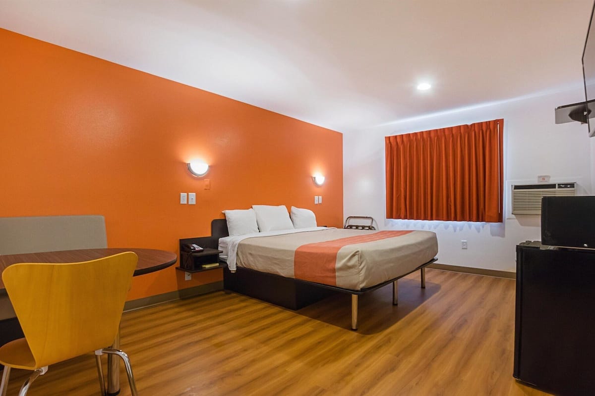 A hotel room with a bed, a desk, a chair, and a television.