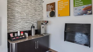 A modern kitchen with a coffee machine, a kettle, and a coffee cup. There are three posters on the wall advertising travel savings. - Motel 6 Marshalltown, IA (Marshalltown)