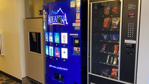 Un distributeur automatique arborant le logo bleu d’AquaFina, proposant des boissons et des en-cas.