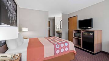A hotel room with a bed, a TV, a microwave, and a refrigerator.