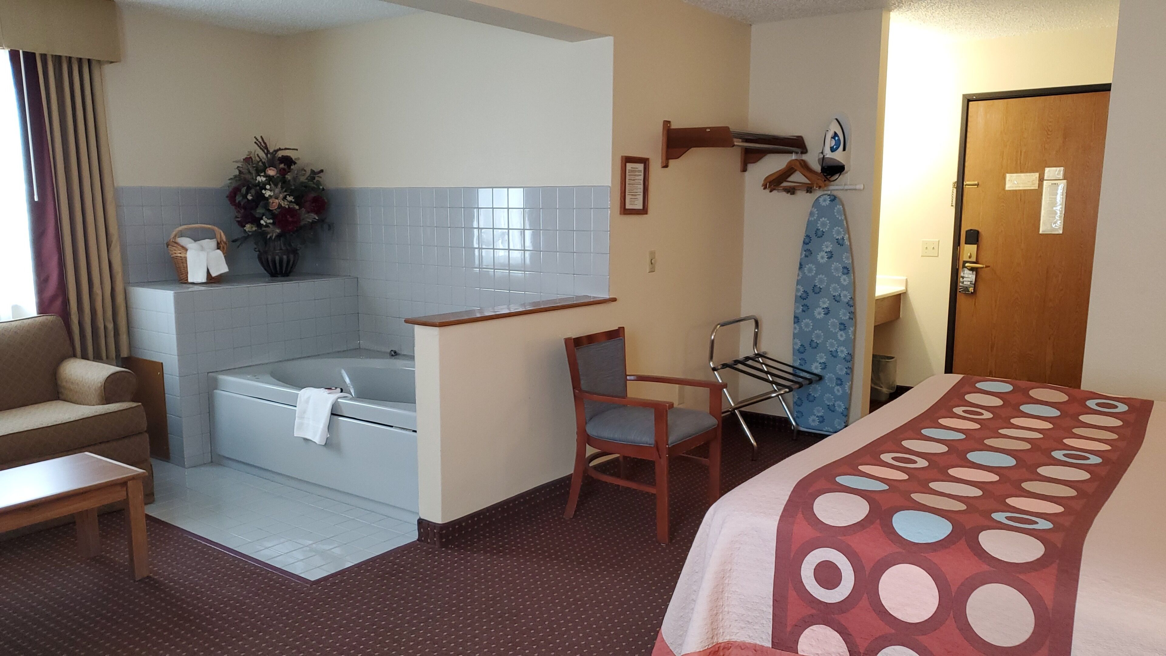 Ein Hotelzimmer mit Badewanne, einem Sessel, einem Bett und einer Tür.