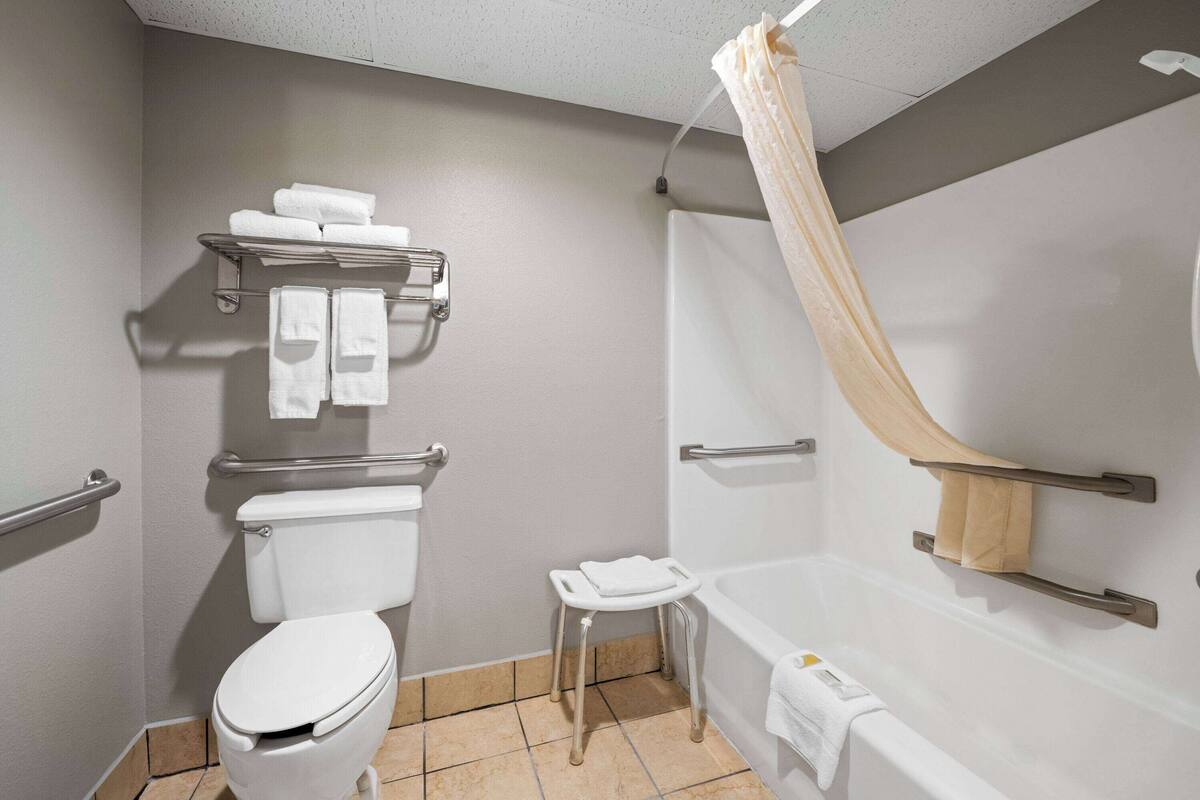 A bathroom with a toilet, a sink, a shower with a curtain, and a towel rack.