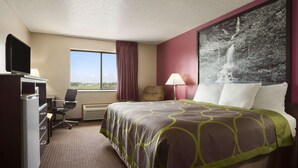 Habitación de hotel con cama, escritorio con computadora, silla, televisor y ventana con vista.
