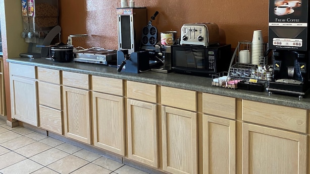 A self-service coffee station with a coffee machine, a microwave, and a beverage dispenser. - Western Inn & Suites (Grinnell)