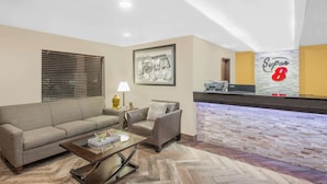 A hotel lobby with a sofa, armchair, and a reception desk with a 'Super 8' sign. - Super 8 by Wyndham Webster City IA (Webster City)