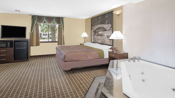 A hotel room with a bed, a TV, a desk, a lamp, and a bathtub. - Super 8 by Wyndham Webster City IA (Webster City)