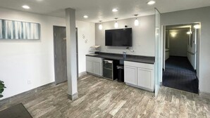 Eine moderne Küche mit Flachbildfernseher, Einbauleuchten und Holzboden.