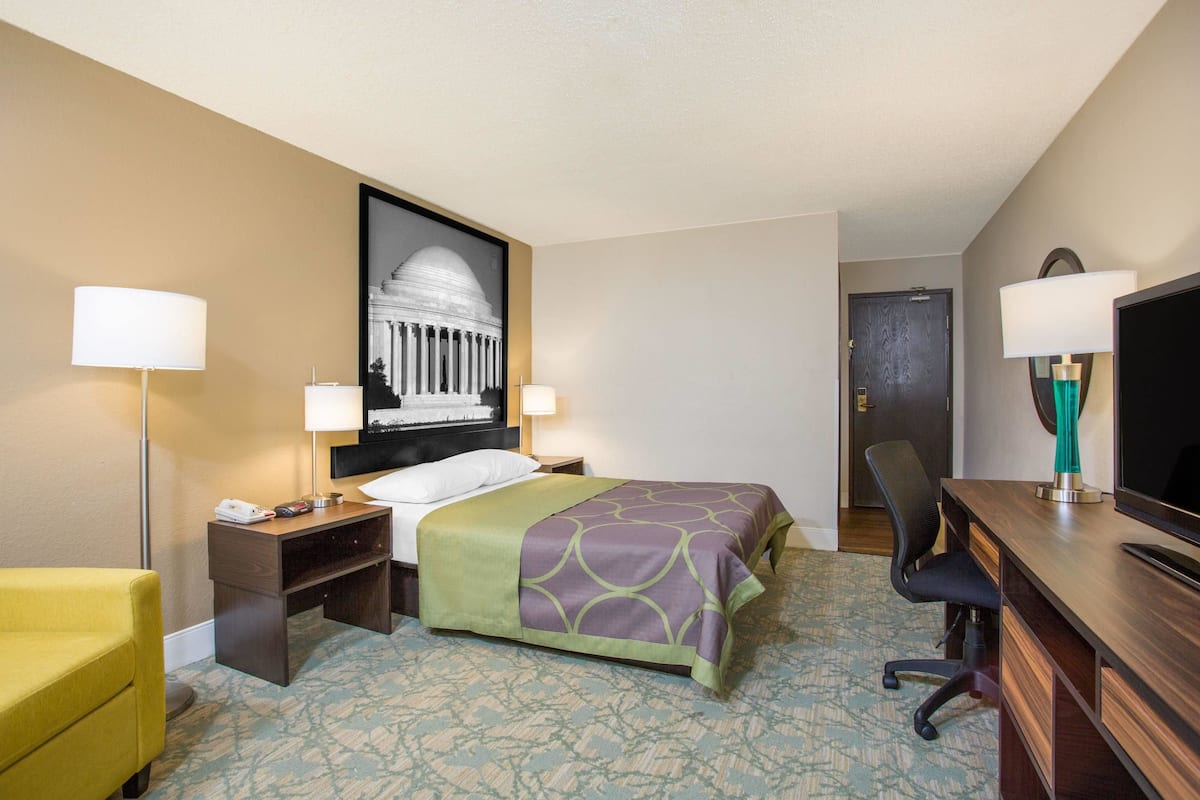 Une chambre d’hôtel équipée d’un lit, d’un bureau, d’une chaise et d’un téléviseur.