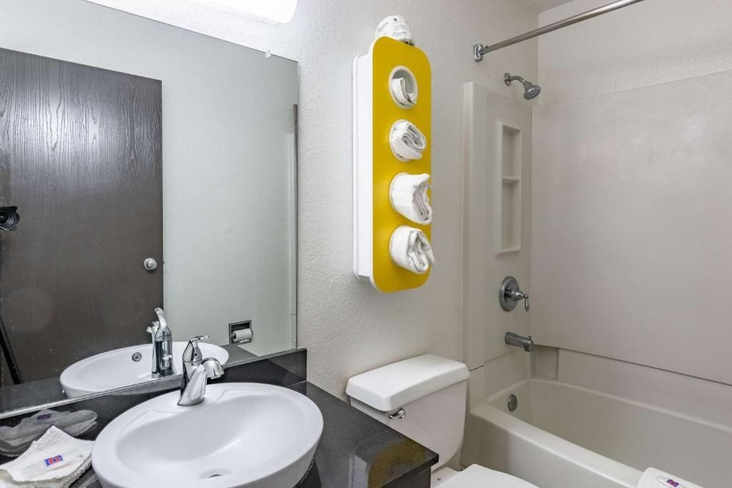 A bathroom with a sink, mirror, toilet, and shower.