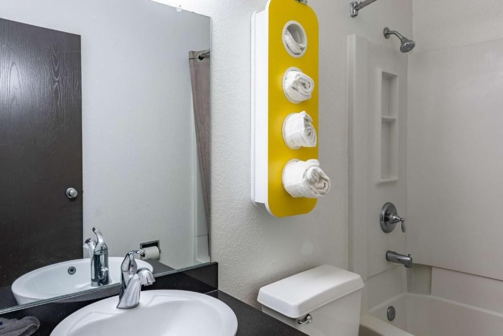 A bathroom with a white sink, a mirror, a toilet, and a shower area.