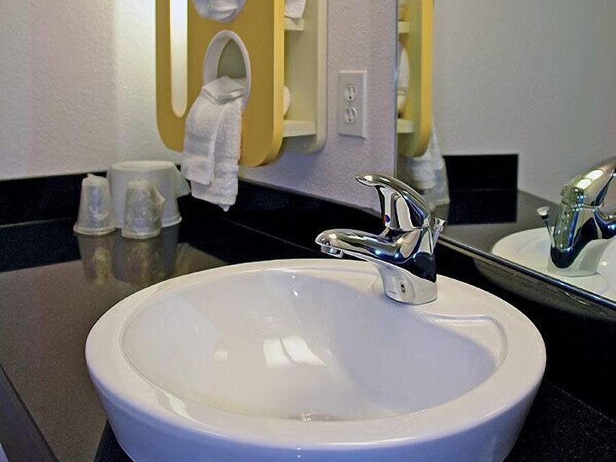 A bathroom with a white sink, a mirror, and a towel rack with multiple towels.