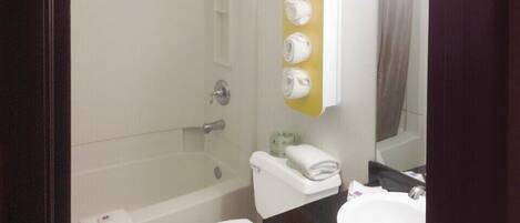 A bathroom with a bathtub, toilet, sink, and a towel rack with towels.