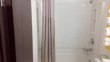 A bathroom with a bathtub, a shower curtain, and a toilet.