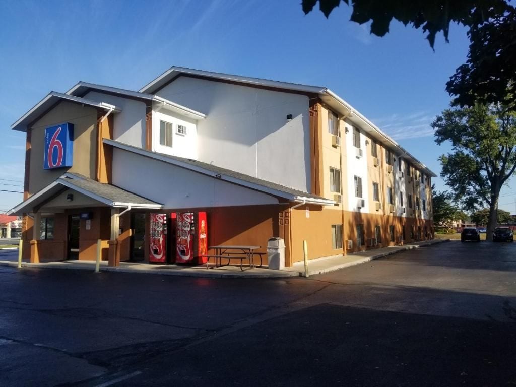 A motel with a flat roof, a covered entrance, and a visible parking area.