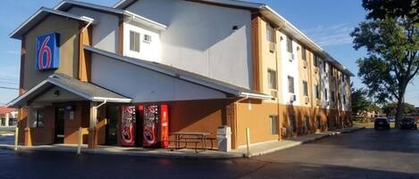 A motel with a flat roof, a covered entrance, and a visible parking area.