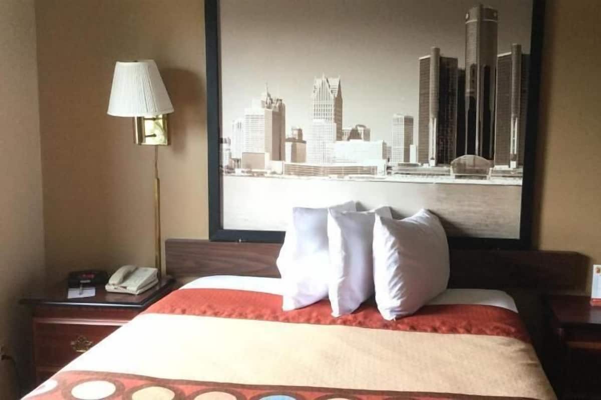 Ein Hotelzimmer mit einem Bett, zwei Nachttischen, einem Telefon und einem Stadtbild an der Wand.
