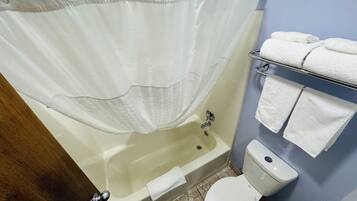 A bathroom with a bathtub, toilet, and towel rack.