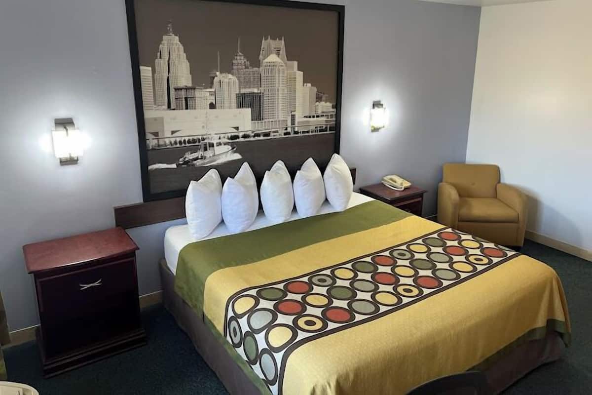 Ein Hotelzimmer mit einem Bett, einem Sessel, einem Nachttisch und einer Wandleuchte.