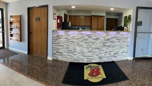 A reception area with a stone counter, wooden cabinets, and a black door labeled "Super 8". - Super 8 by Wyndham Imlay City (Imlay City)
