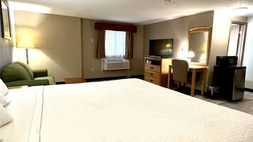 A hotel room with a large bed, a desk with a chair, a television, and a microwave.