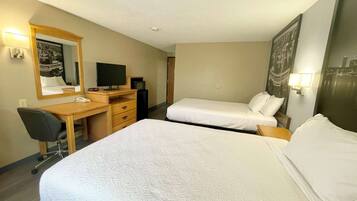Quarto de hotel com duas camas, uma escrivaninha com computador, televisão e espelho.