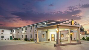Un motel con ingresso coperto, diverse camere e un parcheggio.