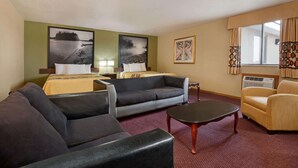Camera d'albergo con due letti, un divano, un tavolino e opere d'arte alle pareti.
