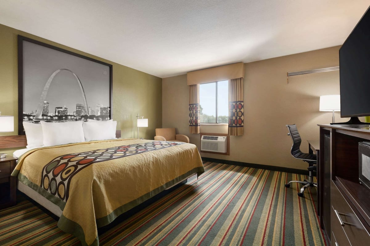 A hotel room with a bed, a desk, a chair, a television, and a window with curtains.
