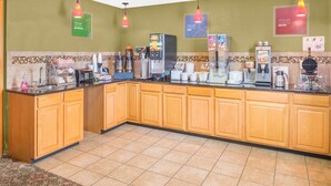 Una cucina d'hotel con un lungo bancone, diversi elettrodomestici e una parete rivestita di piastrelle.