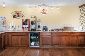 A breakfast bar with a coffee machine, a refrigerator, and a sign indicating a breakfast service. - Super 8 by Wyndham Warrensburg (Warrensburg)