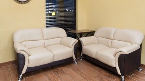 Twee beige leren banken met zwarte poten, een kleine ronde tafel en een wandklok.