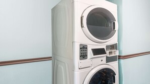 Een gestapelde wasmachine en droger tegen een lichtblauwe muur met houten sierlijsten.