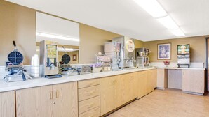 A kitchen with a long counter, various appliances, and cabinets.
