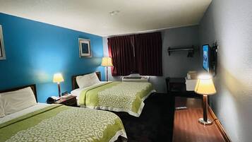 A hotel room with two beds, a desk, a chair, a TV, and a window with curtains.