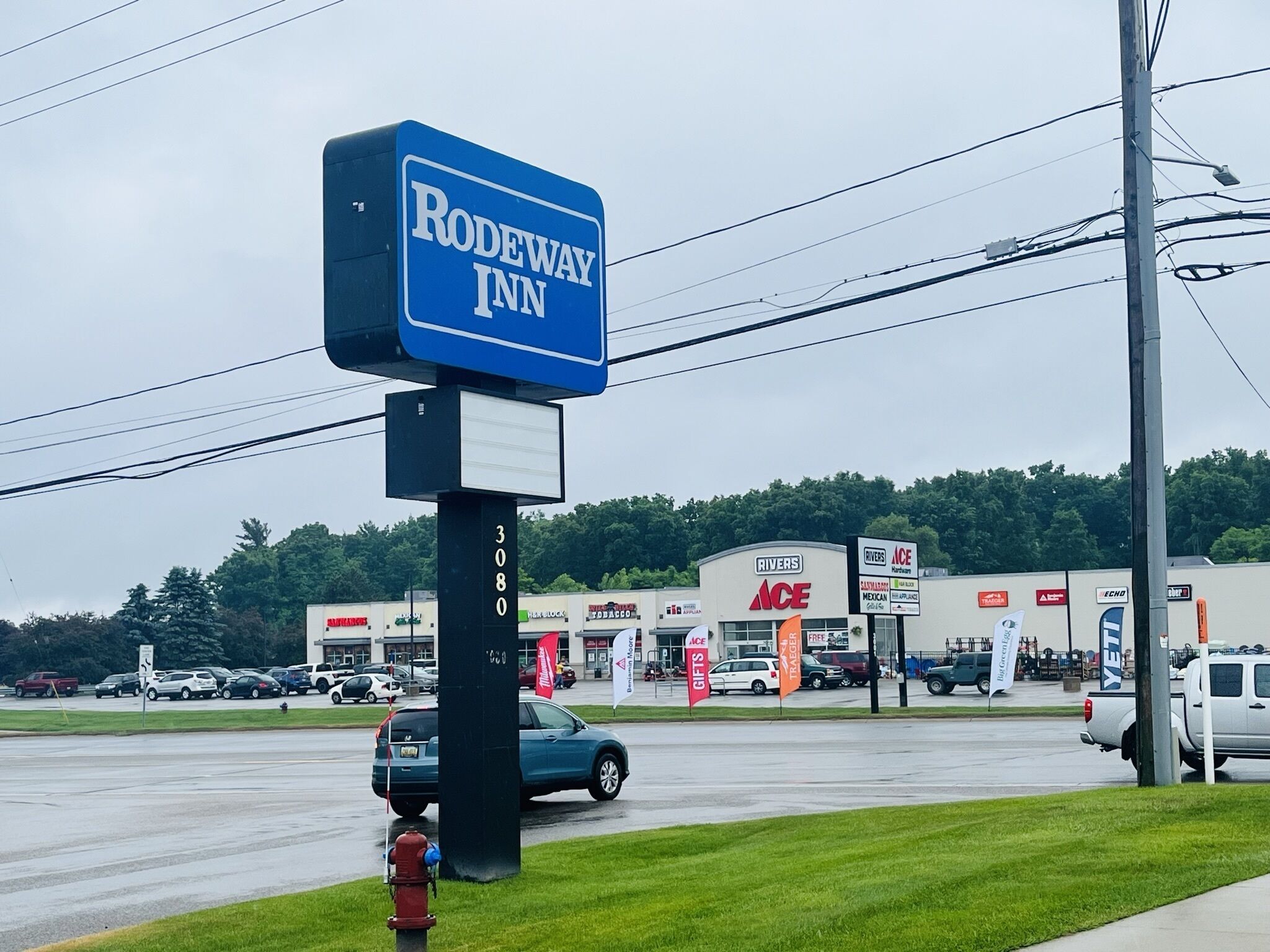 Señal de Rodeway Inn y un edificio con letreros ACE y RIVERS.