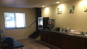 A kitchen with a dining table, a counter with a coffee machine, and a staircase.