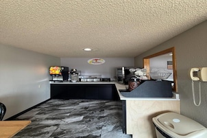 Habitación de hotel compacta con kitchenette, un pequeño comedor, un cubo de basura y un teléfono en la pared.