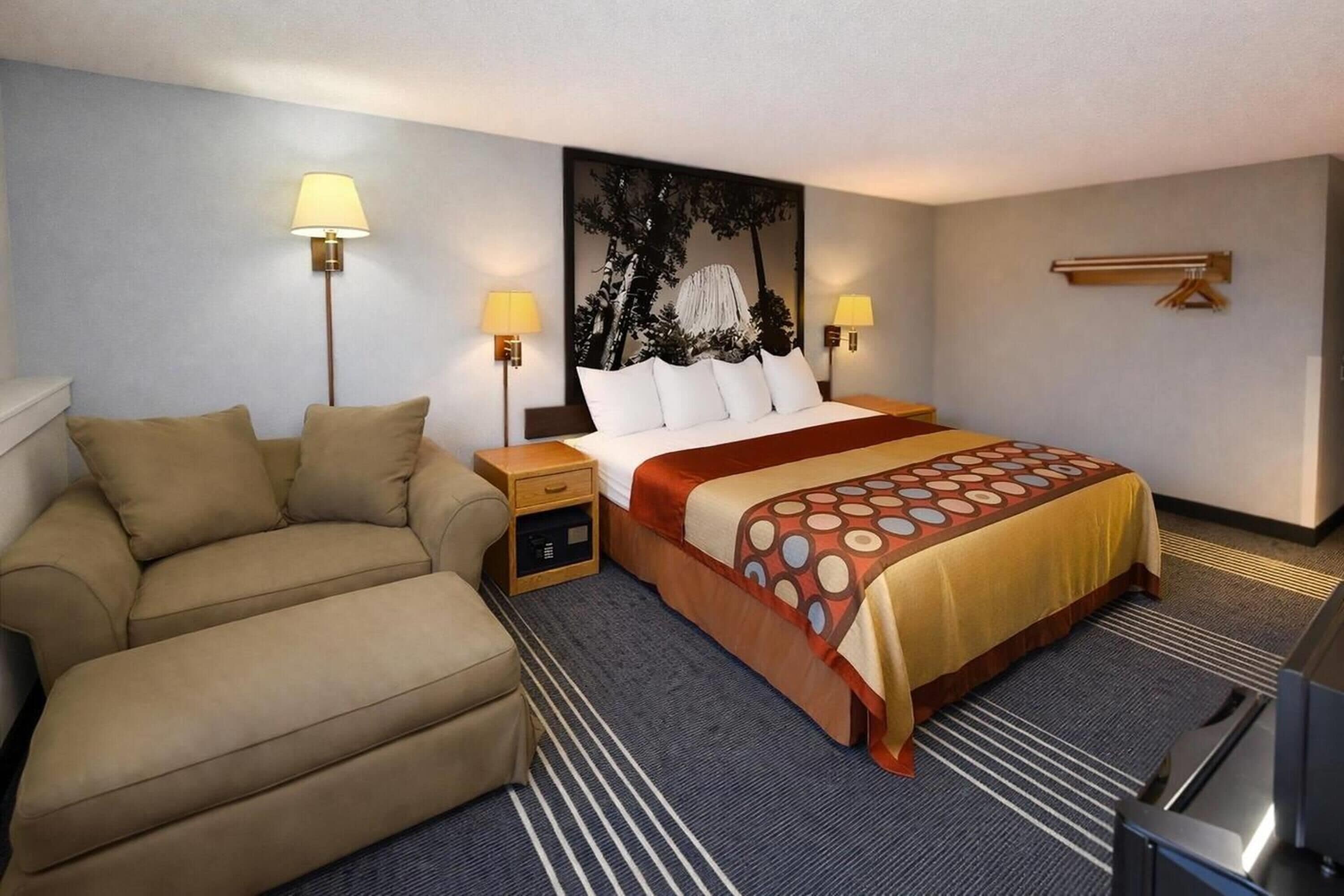 Een hotelkamer met een bed, twee nachtkastjes met lampen, een bank, een televisie en een wandradiator.