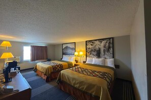 Een hotelkamer met twee bedden, een bureau, lampen en kunstwerken aan de muren.