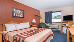 A hotel room with a bed, a desk, a chair, a television, and a window with curtains. - Super 8 by Wyndham Baxter/Brainerd Area (Baxter)