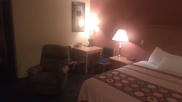 Una habitación de hotel con una cama, un escritorio, una silla y una lámpara.